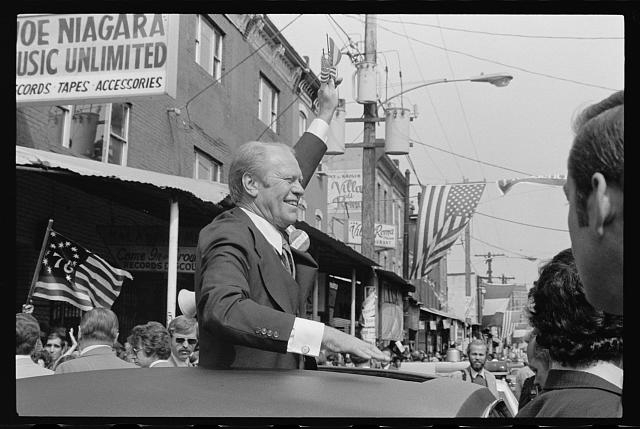 [President Gerald Ford waves to crowd from the sunroof of...