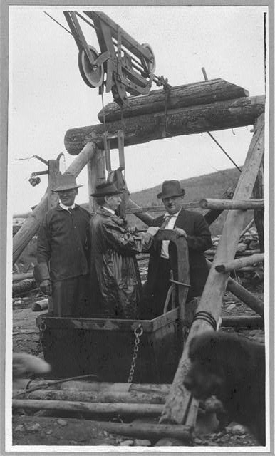 Frank G. Carpenter in middle of bucket at gold mine