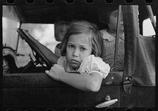 Child of farmer sitting in automobile waiting for father...
